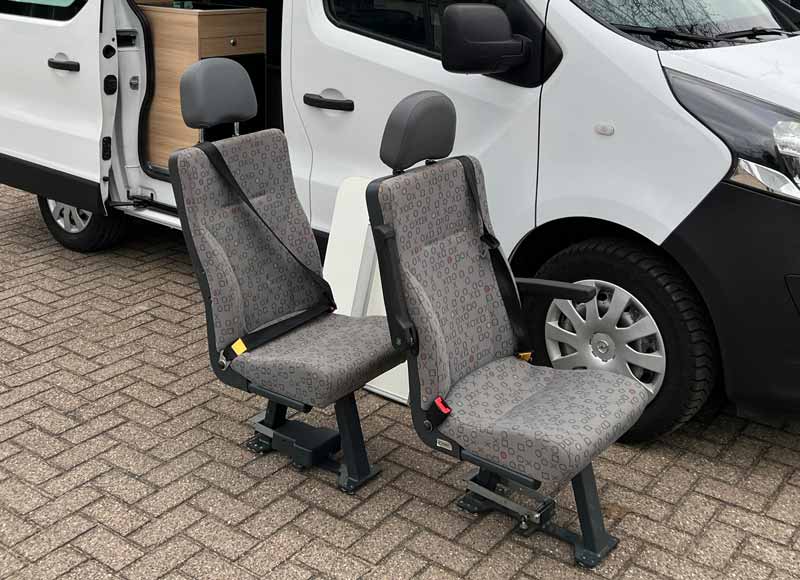 Losse stoelen voor op vloerrails langs een camper